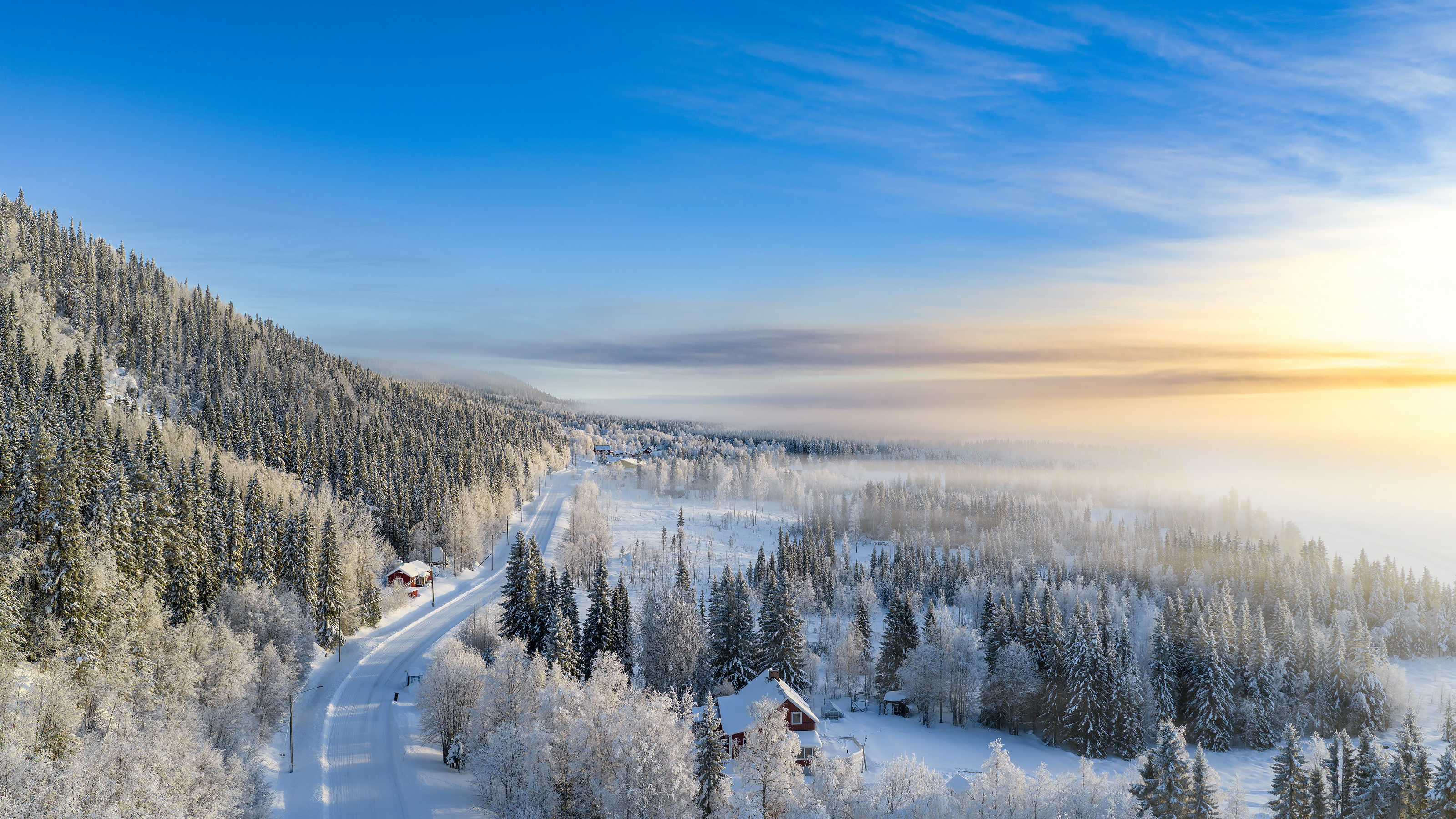 Winter sunrise over a snowbound valley with red cabins - the road to the mountain camp